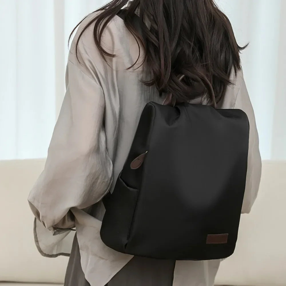 Person wearing a black backpack indoors with a neutral background