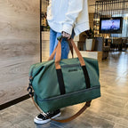 Person holding a green duffel bag with brown straps in a modern indoor setting.